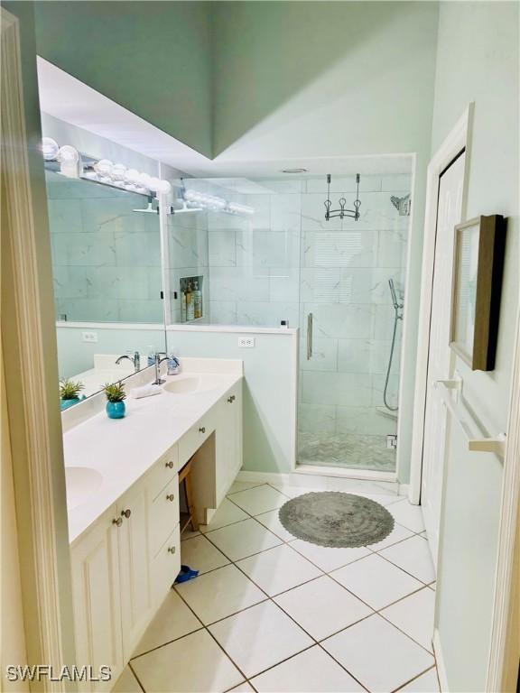 full bath with a stall shower, double vanity, and tile patterned flooring