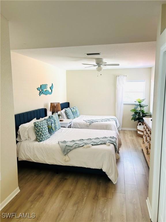 bedroom with light wood finished floors, ceiling fan, and baseboards