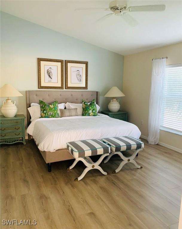 bedroom with lofted ceiling, wood finished floors, baseboards, and ceiling fan