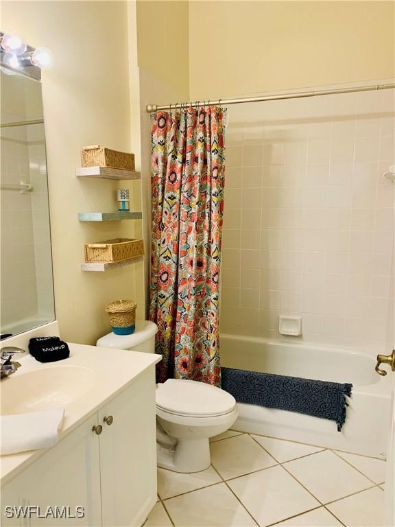 full bath featuring toilet, shower / tub combo with curtain, tile patterned floors, and vanity