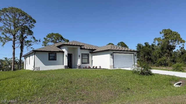 prairie-style house featuring concrete driveway, an attached garage, stucco siding, and a front yard