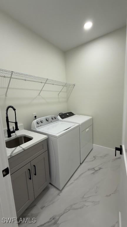 washroom featuring a sink, cabinet space, marble finish floor, separate washer and dryer, and baseboards