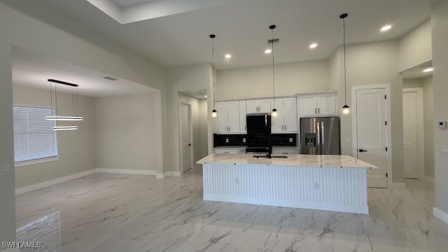 kitchen featuring stainless steel fridge, baseboards, and a center island with sink