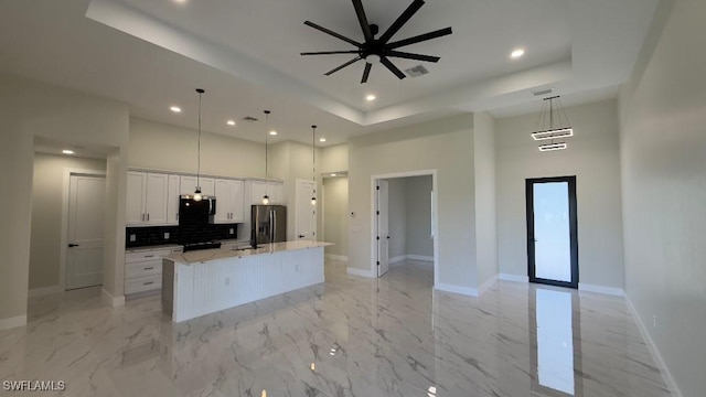 kitchen featuring stainless steel appliances, recessed lighting, a ceiling fan, a raised ceiling, and a high ceiling
