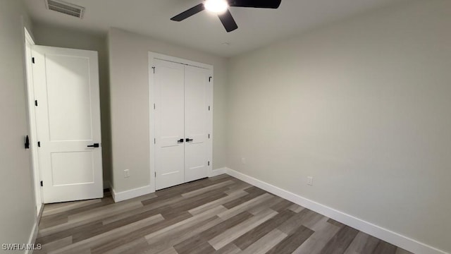 unfurnished bedroom with baseboards, a closet, visible vents, and wood finished floors