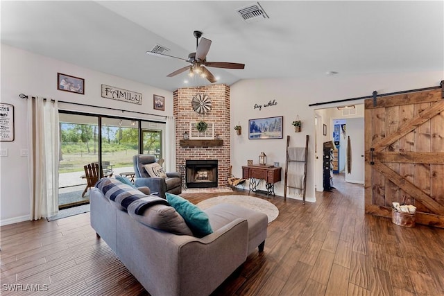 living area with a barn door, a ceiling fan, visible vents, and wood finished floors