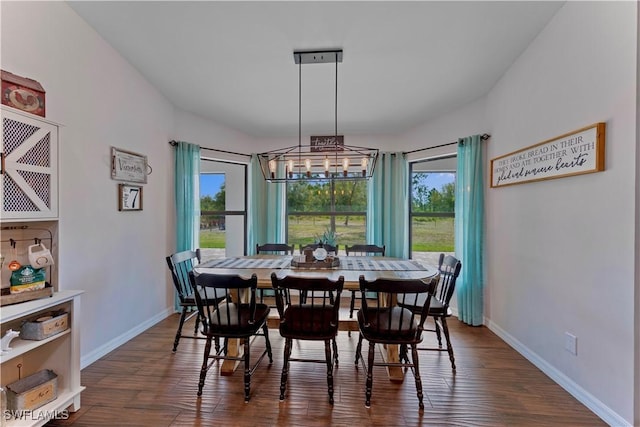 dining space featuring a chandelier, baseboards, and dark wood finished floors