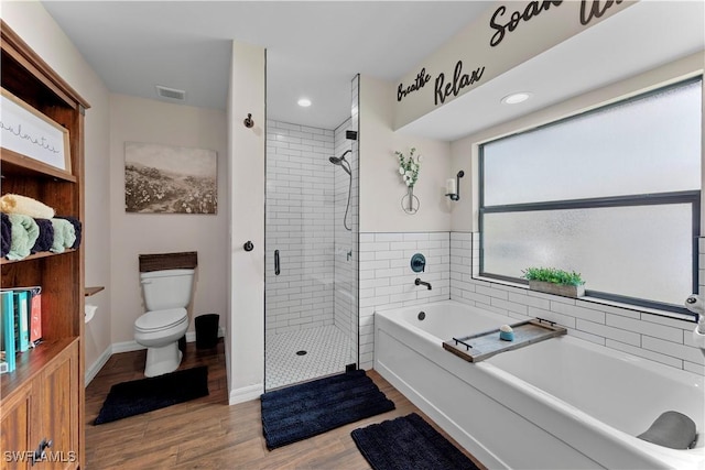 bathroom featuring toilet, wood finished floors, a stall shower, a bath, and visible vents