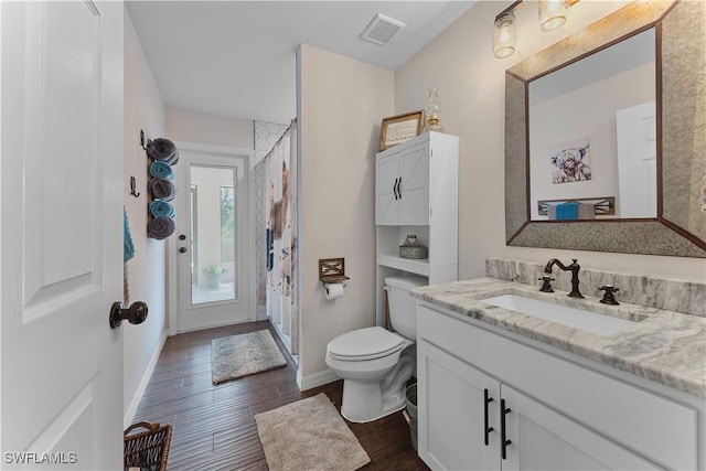 bathroom with toilet, wood finished floors, visible vents, baseboards, and vanity