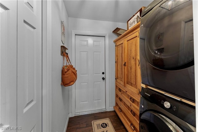laundry area featuring baseboards, stacked washer / dryer, cabinet space, and dark wood-type flooring