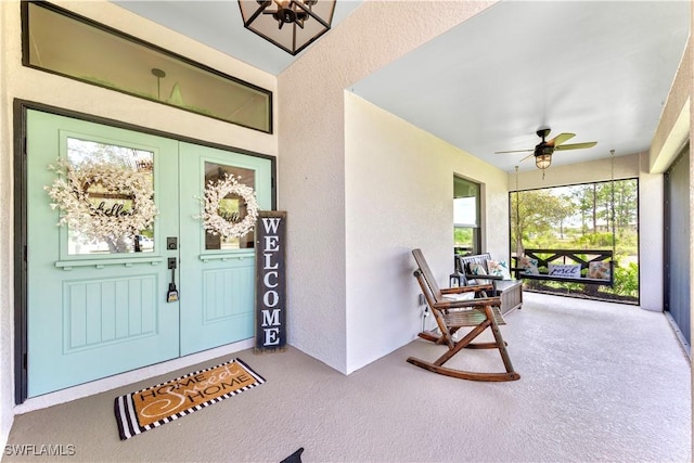 entrance to property with covered porch, stucco siding, french doors, and ceiling fan