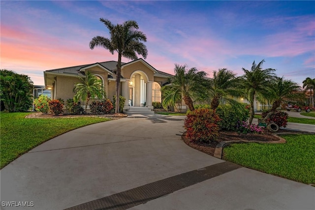 5010 La Costa Island Ct, Punta Gorda, FL 33950 - view of front of house with curved driveway, stucco siding, and a lawn