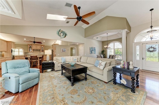 5010 La Costa Island Ct, Punta Gorda, FL 33950 - living area with a ceiling fan, light wood-style flooring, high vaulted ceiling, a chandelier, and ornate columns