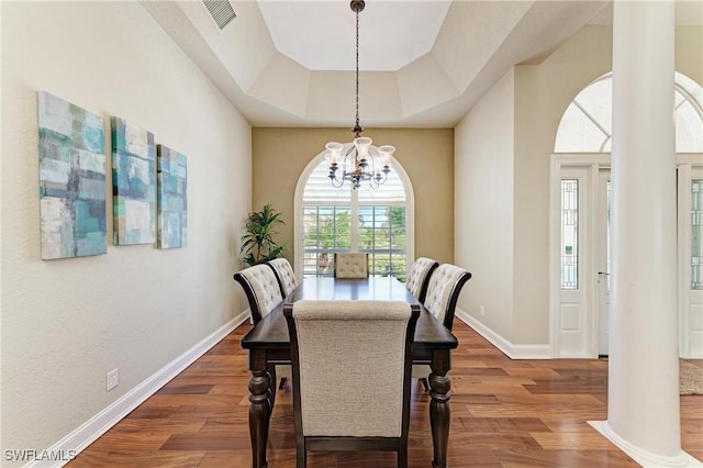 5010 La Costa Island Ct, Punta Gorda, FL 33950 - dining area featuring a chandelier, wood finished floors, a tray ceiling, baseboards, and arched walkways