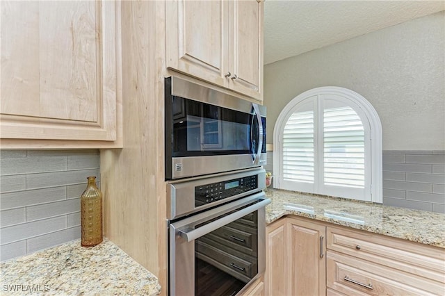 5010 La Costa Island Ct, Punta Gorda, FL 33950 - kitchen with appliances with stainless steel finishes, light brown cabinets, light stone counters, and backsplash