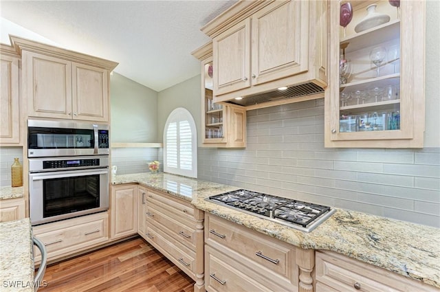 5010 La Costa Island Ct, Punta Gorda, FL 33950 - kitchen with appliances with stainless steel finishes, vaulted ceiling, tasteful backsplash, light wood-type flooring, and glass insert cabinets