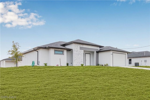 prairie-style home with driveway, an attached garage, central AC, stucco siding, and a front yard