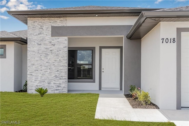 doorway to property featuring a yard and stucco siding
