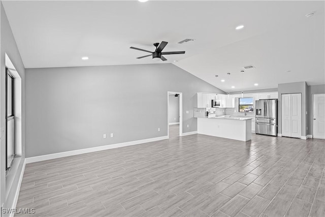 unfurnished living room with ceiling fan, lofted ceiling, baseboards, and visible vents