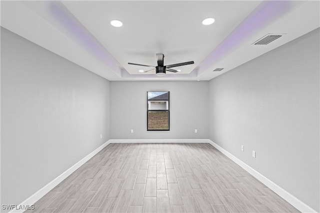 spare room with light wood finished floors, a tray ceiling, visible vents, ceiling fan, and recessed lighting
