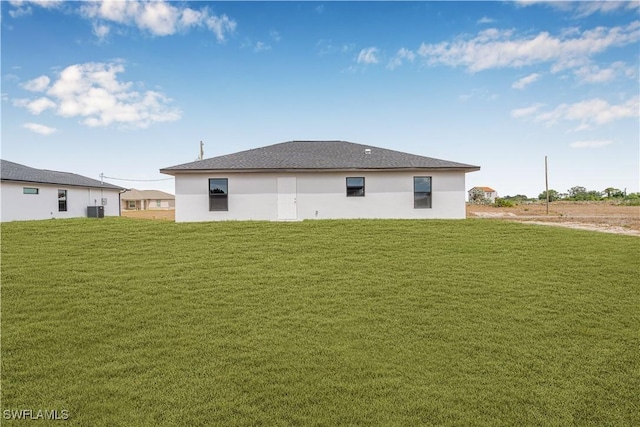 rear view of property featuring central air condition unit, a yard, and stucco siding
