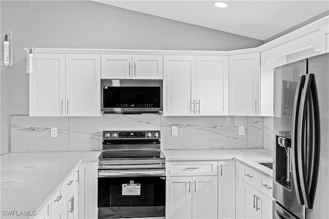 kitchen featuring vaulted ceiling, stainless steel appliances, white cabinetry, and backsplash