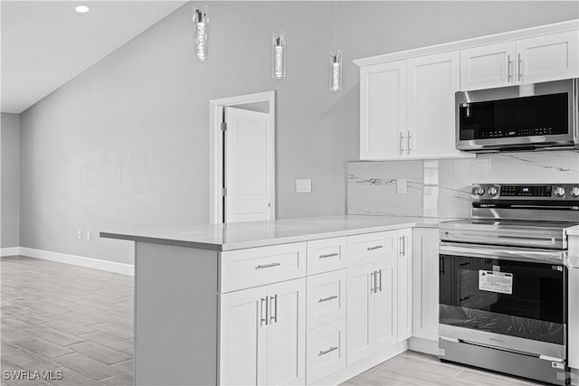 kitchen featuring appliances with stainless steel finishes, decorative light fixtures, a peninsula, white cabinets, and light wood-type flooring