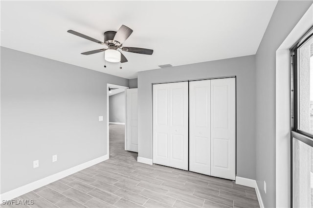 unfurnished bedroom with a closet, baseboards, light wood-style flooring, and ceiling fan