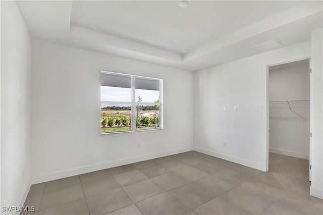44494 Little Blue Heron Way, Punta Gorda, FL 33982 - unfurnished bedroom featuring a tray ceiling, a spacious closet, baseboards, light tile patterned flooring, and a closet