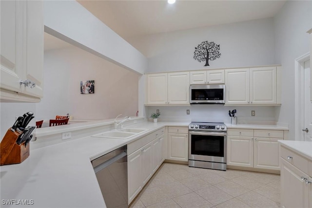 8546 Silk Oak Ln, Naples, FL 34119 - kitchen with stainless steel appliances, a sink, lofted ceiling, light countertops, and white cabinetry