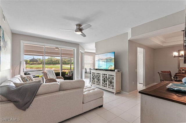 living area featuring a ceiling fan, light tile patterned flooring, a chandelier, and baseboards