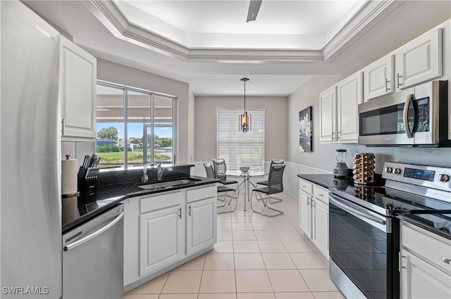 kitchen with stainless steel appliances, a sink, a raised ceiling, white cabinets, and light tile patterned floors