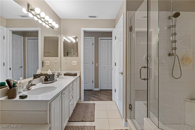 full bath featuring a stall shower, double vanity, and tile patterned floors