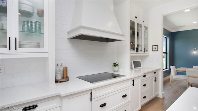 2954 Cinnamon Bay Cir, Naples, FL 34119 - kitchen featuring premium range hood, black electric cooktop, tasteful backsplash, white cabinetry, and ornamental molding