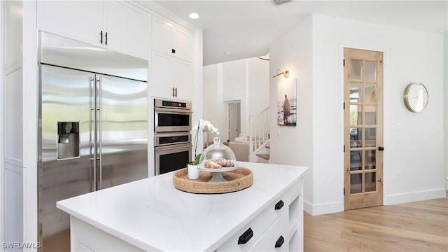 2954 Cinnamon Bay Cir, Naples, FL 34119 - kitchen with appliances with stainless steel finishes, light wood-style floors, white cabinets, baseboards, and light countertops