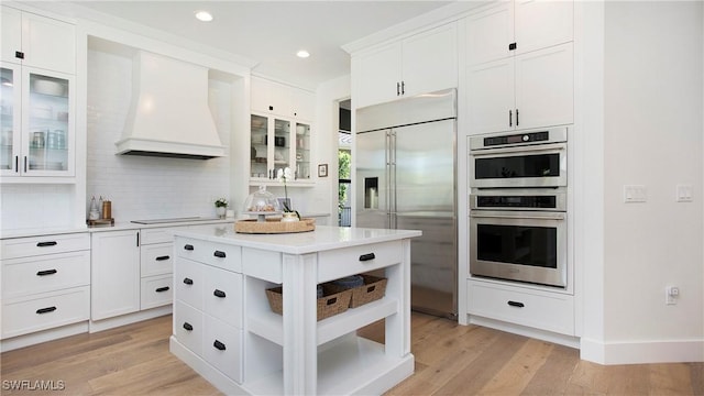 2954 Cinnamon Bay Cir, Naples, FL 34119 - kitchen with appliances with stainless steel finishes, light countertops, white cabinets, tasteful backsplash, and premium range hood
