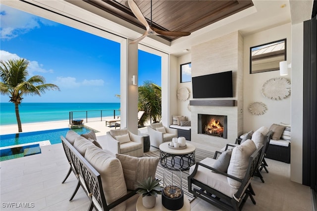 26924 Hickory Blvd, Bonita Springs, FL 34134 - view of patio / terrace with an outdoor living space with a fireplace, a ceiling fan, view of nearby beach, and an outdoor pool