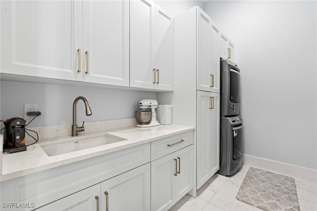 388 Pine Ave, Naples, FL 34108 - kitchen with stacked washer / dryer, a sink, white cabinetry, light marble finish floors, and light stone countertops