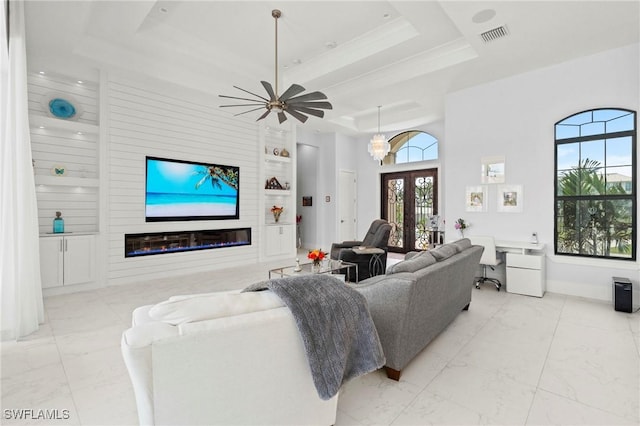 388 Pine Ave, Naples, FL 34108 - living room featuring built in features, marble finish floors, a tray ceiling, a glass covered fireplace, and french doors