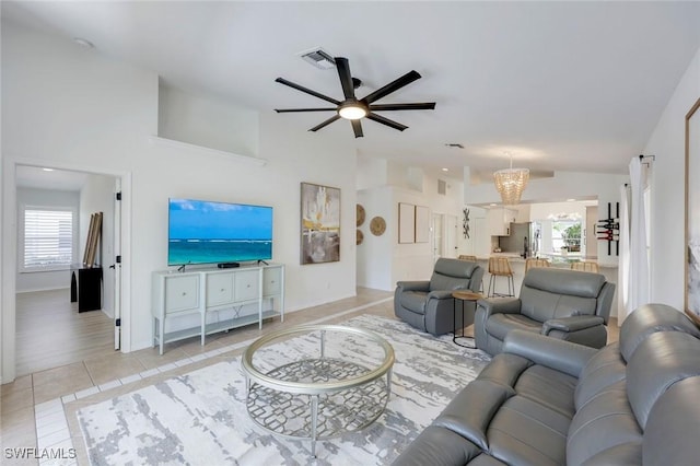 living area with a ceiling fan, lofted ceiling, light tile patterned floors, and baseboards