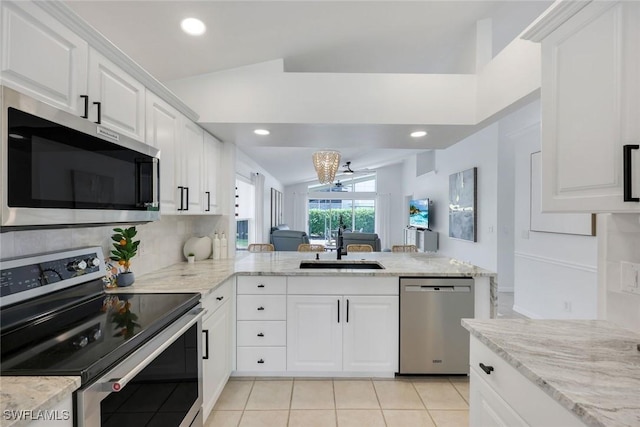 kitchen featuring stainless steel appliances, vaulted ceiling, a sink, light tile patterned floors, and a chandelier