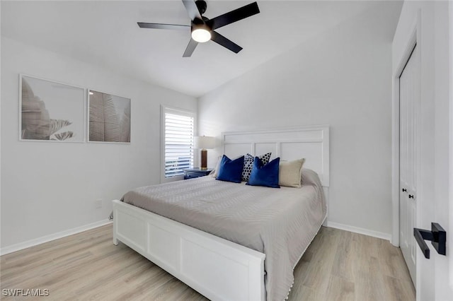 bedroom with light wood finished floors, a closet, baseboards, vaulted ceiling, and a ceiling fan