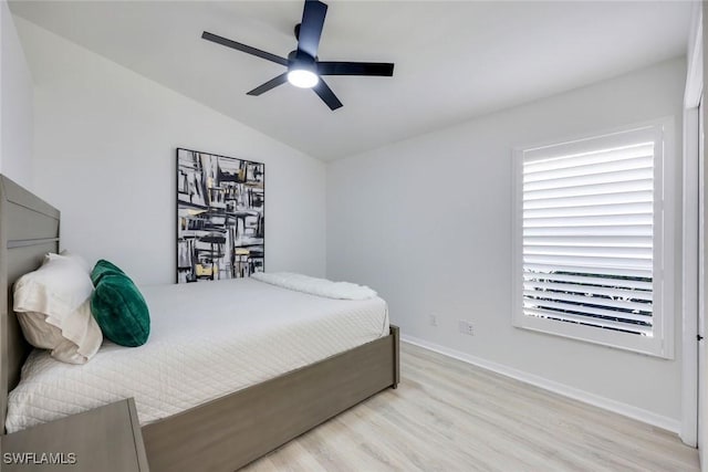 bedroom with wood finished floors, lofted ceiling, baseboards, and a ceiling fan