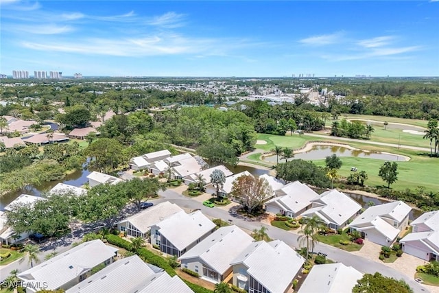 aerial perspective of suburban area with a golf course, a nearby body of water, and a tree filled landscape