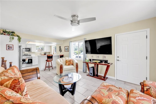 living room featuring ceiling fan, light tile patterned floors, and baseboards