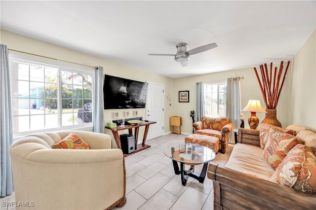 living area with a ceiling fan, light tile patterned floors, and baseboards