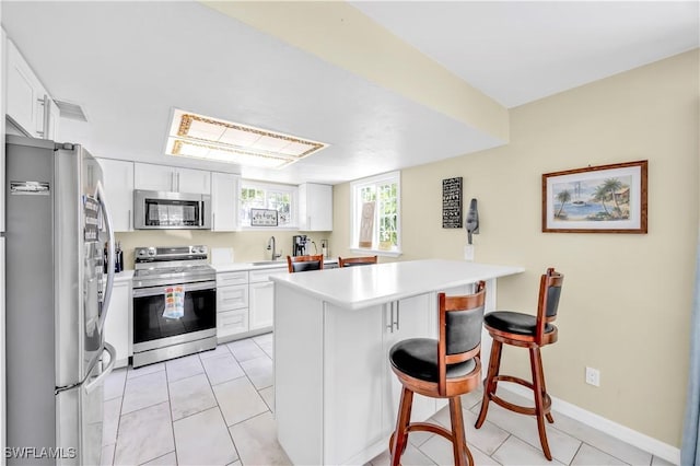 kitchen with appliances with stainless steel finishes, a sink, a peninsula, and white cabinets