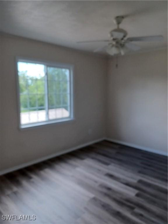 spare room with healthy amount of natural light, wood finished floors, and baseboards