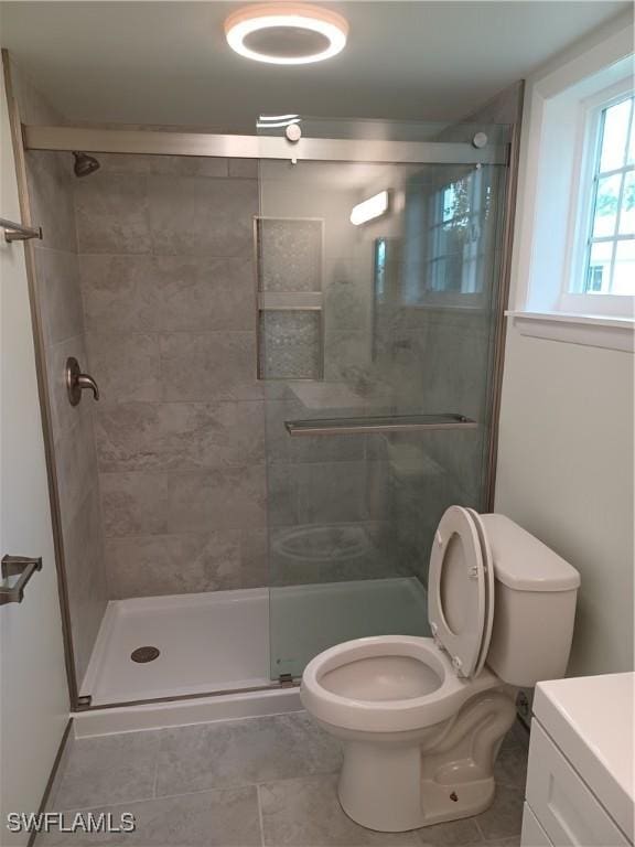 bathroom with toilet, a shower stall, tile patterned floors, and vanity