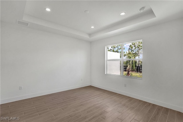 44287 Panther Dr, Punta Gorda, FL 33982 - empty room featuring a tray ceiling, wood finished floors, baseboards, and recessed lighting